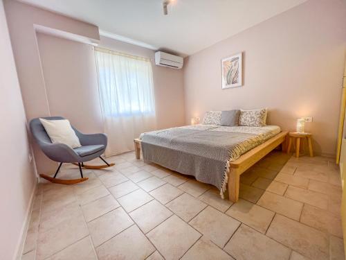 a bedroom with a bed and a chair and a window at Eco Sunshine Apartments Lumbarda in Lumbarda