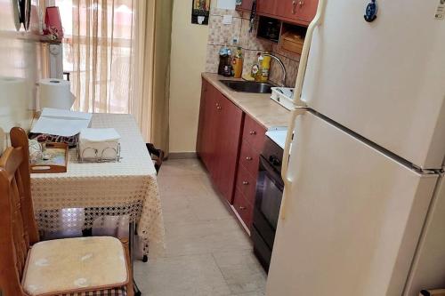 eine Küche mit einem weißen Kühlschrank und einem Tisch in der Unterkunft Christie's Apartment in Agrinio