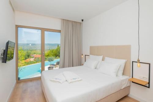 a bedroom with a white bed and a large window at Luxury Villa Blue with a pool in Zmijavci