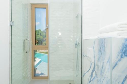a bathroom with a glass shower with a window at Luxury Villa Blue with a pool in Zmijavci