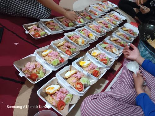 una mesa con muchas bandejas de comida. en Vila Anggur Pintukabun, en Bukittinggi