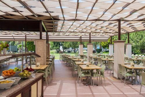 Aqua Fantasy Aquapark Hotel & Spa - Ultra All Inclusive في كوساداسي: منطقة لتناول الطعام في الهواء الطلق مع طاولات وكراسي