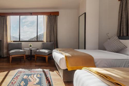 a hotel room with two beds and a table and chairs at Hotel Dralha in Thimphu
