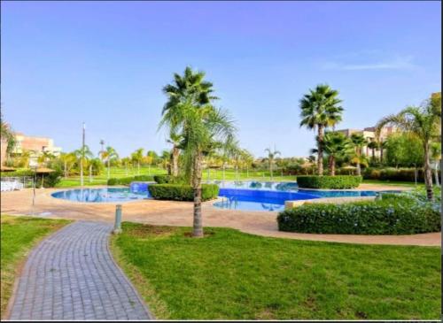 einen Park mit zwei Pools und Palmen und einem Bürgersteig in der Unterkunft Mary in Ksar et Tlatia