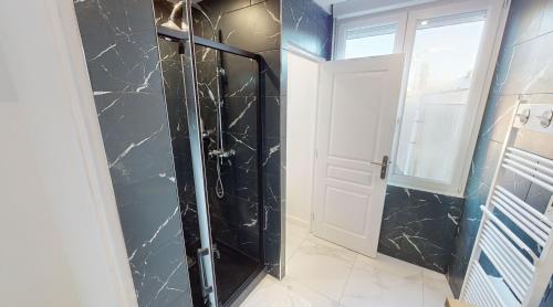 een badkamer met een douche en zwarte marmeren muren bij Les meublés touristiques - Saint Théodore en face du Louvre-Lens in Lens