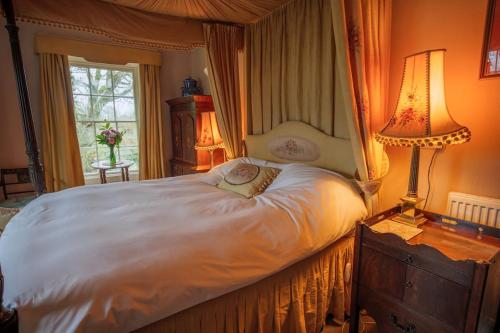 um quarto com uma grande cama branca e 2 candeeiros em Gelly Dylan Thomas Paradise em Lampeter