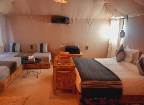 a room with two beds and a desk in a room at Night sky luxury camp in Adrouine