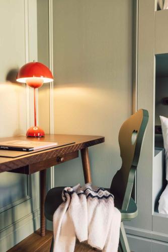 a desk with a lamp and a chair with towels on it at Posthotel Taube in Schruns-Tschagguns