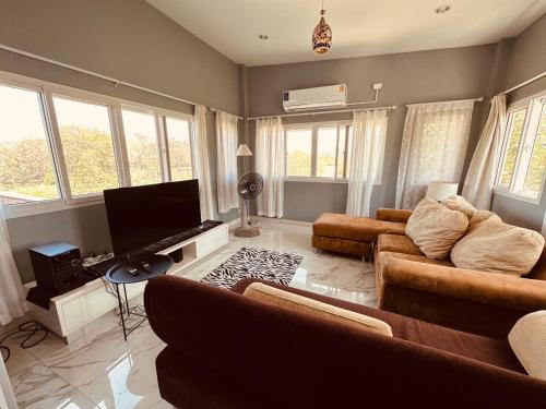 een woonkamer met banken en een flatscreen-tv bij บ้านบนภู ปากช่อง พลูวิลล่า - with a housekeeper in Ban Lam Thong Lang