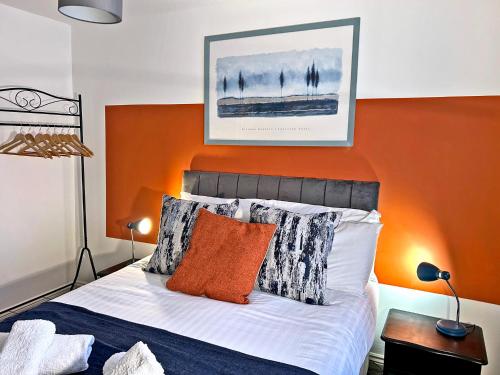 um quarto com uma parede laranja e uma cama com almofadas em Hindmarsh Apartment em Ashington