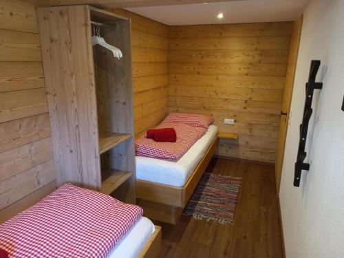 two beds in a room with wooden walls at Hennleiten Hof in Reith bei Kitzbühel