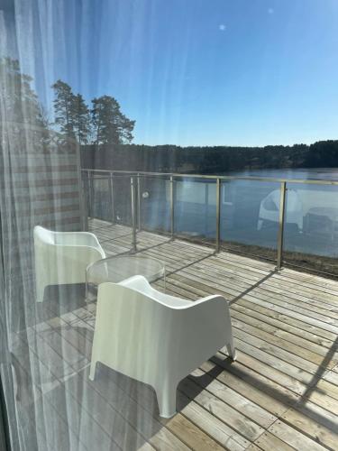 a balcony with two white chairs and a view of the water at Perła Jezior in Ruciane-Nida