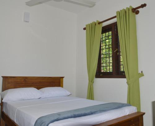 een slaapkamer met een bed en een raam met groene gordijnen bij Oceanic Shades - Mount Lavinia in Mount Lavinia
