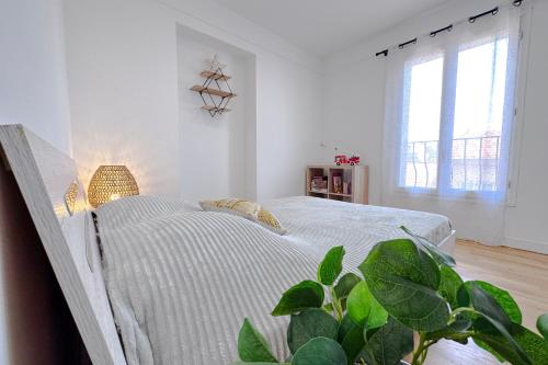 - une chambre blanche avec un lit et une plante dans l'établissement BELLET - Rooftop, jacuzzi et vue imprenable sur Nice et Mer, à Nice
