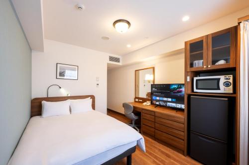 pokój hotelowy z łóżkiem i telewizorem w obiekcie Hotel New Yokosuka w mieście Yokosuka