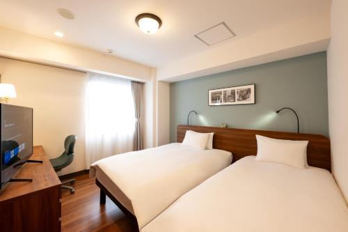 a hotel room with two beds and a television at Hotel New Yokosuka in Yokosuka