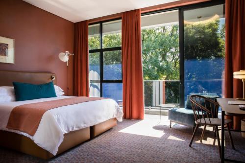 a bedroom with a bed and a desk and a large window at Home Suite Hotels Rosebank in Johannesburg