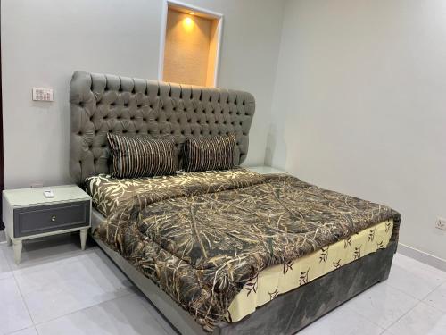 a bed in a room with a large headboard at Park View Residency in Rawalpindi
