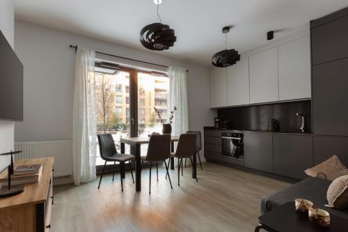 a kitchen and dining room with a table and chairs at Scala Apartamenty by Moderna Profit- Łąkowa 60C in Gdańsk