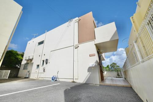 an exterior view of a white building at 最大１２人宿泊可能 ご友人家族と一緒にステイタイム 広々リビングでホームパーティー in Uruma