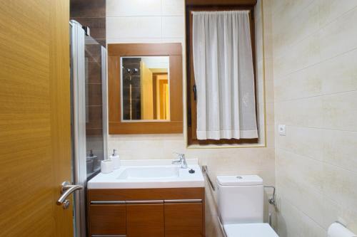 a bathroom with a sink and a toilet and a mirror at La Casa del Muelle in Suances