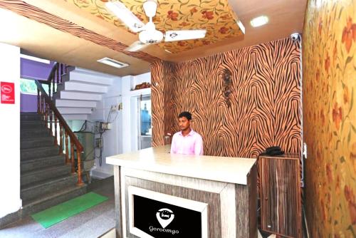 Un uomo in piedi dietro un bancone in una stanza di Goroomgo D2 Holiday inn Near Sea Beach a Puri