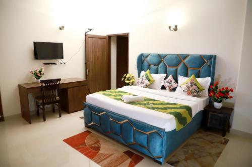 a bedroom with a bed with a blue headboard and a desk at Fortune Home Service Apartment 3Bhk,E-28, Saket 2B in New Delhi