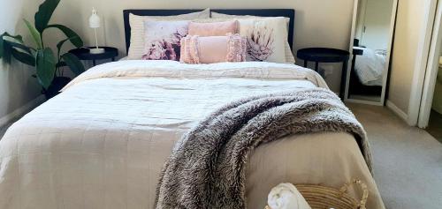 Una cama con almohadas rosas y una manta. en Ballarat Holiday Homes - Lake Wendouree - Near Ballarat Grammar - 3 kms to Ballarat Hospitals, en Ballarat