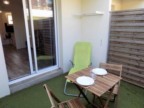 une table et des chaises en bois sur une terrasse avec une fenêtre dans l'établissement Royan - JOLI NID DOUILLET - résidence MINERVE - proche commerces et plages, à Royan