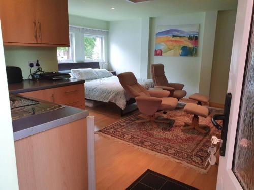 uma cozinha com uma sala de estar com uma cama e cadeiras em Peace and quiet on The Limes em Motcombe