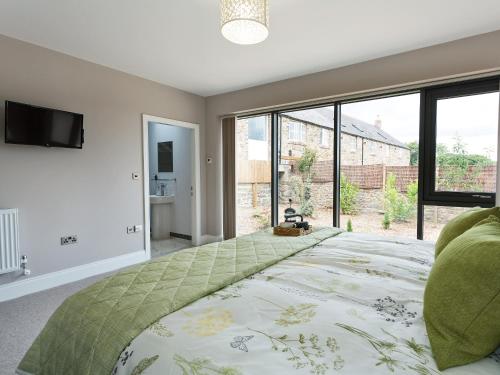 a bedroom with a large bed with a large window at The Cart Shed in Witton Gilbert