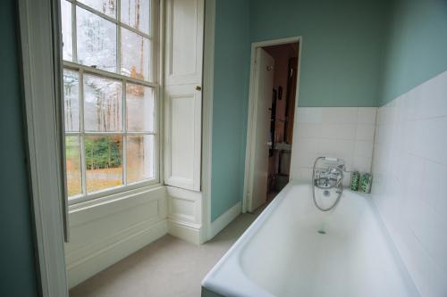 ein Bad mit einer weißen Badewanne und einem Fenster in der Unterkunft Gelly Dylan Thomas Paradise in Lampeter