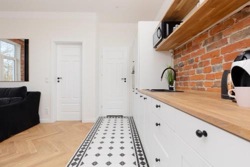 a kitchen with white cabinets and a brick wall at Warsaw Pruszków Park View Comfortable Apartments by Noclegi Renters in Pruszków