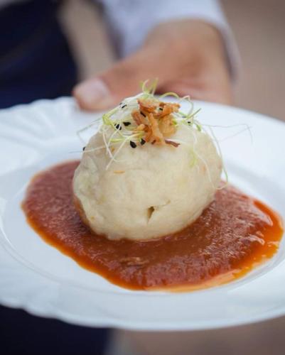 a person holding a plate of food with sauce at Csodaszarvas Vendégházak in Rábahidvég