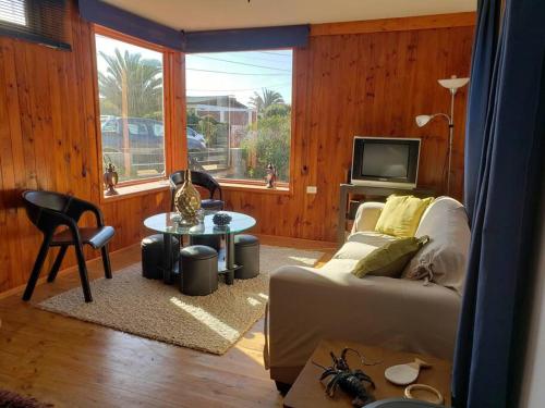 sala de estar con sofá y TV en Linda, cómoda y acogedora casa para 6, en Pichidangui