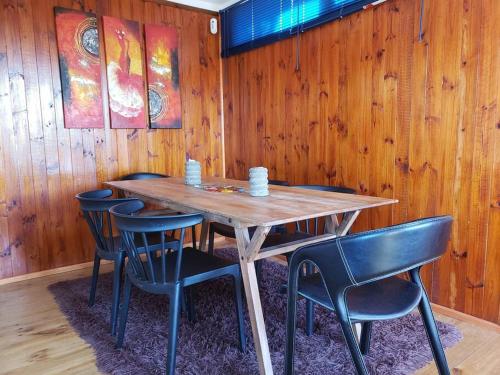 una mesa de madera con sillas y una pared de madera en Linda, cómoda y acogedora casa para 6, en Pichidangui