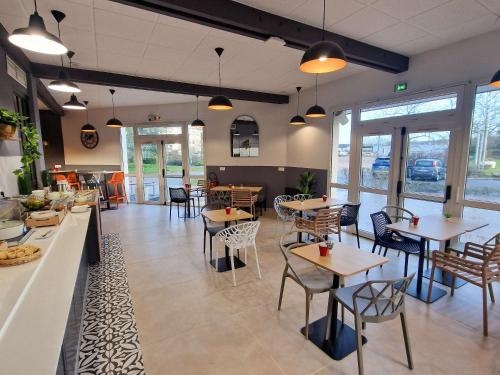 un restaurant avec des tables, des chaises et des fenêtres dans l'établissement ibis Rambouillet, à Rambouillet