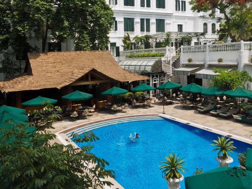 uma vista superior para uma piscina com guarda-sóis verdes em Sofitel Legend Metropole Hanoi em Hanói