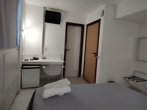 a bedroom with a bed and a desk and a sink at Hotel Oscar Gold Savassi in Belo Horizonte