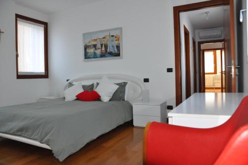 a bedroom with a bed and a table and a red chair at Ex Casa degli Artisti in Montebelluna