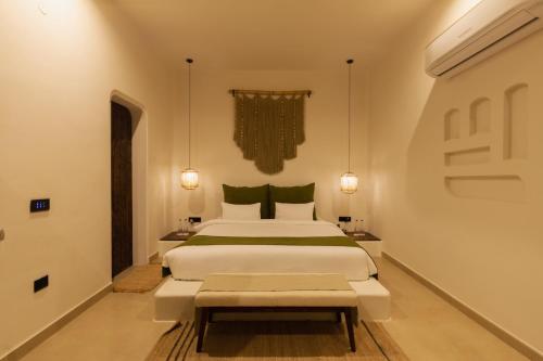 a bedroom with a large white bed and a bench at LA VIDA RETREAT in Jaipur
