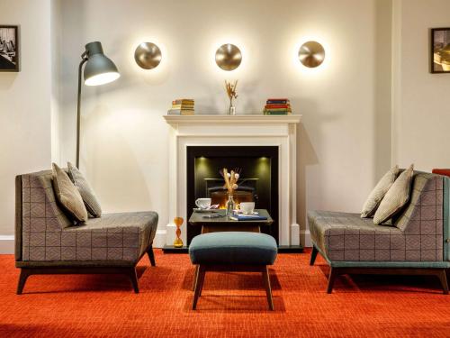 a living room with two chairs and a fireplace at Mercure Telford Centre Hotel in Telford