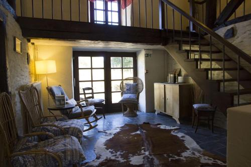 a living room with a staircase and chairs and a table at Gîte écologique 14 pers. à Taverneux - Houffalize in Houffalize
