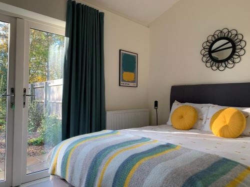 a bedroom with a bed with yellow pillows and a window at Oak Cottage at Gravel Farm in Stretham