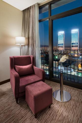 a living room with a chair and a large window at Hilton Garden Inn Izmir Bayrakli in Izmir