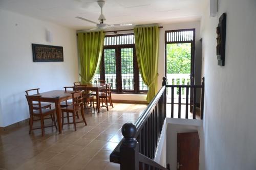 a dining room with a table and chairs and windows at Oceanic Shades - Mount Lavinia in Mount Lavinia