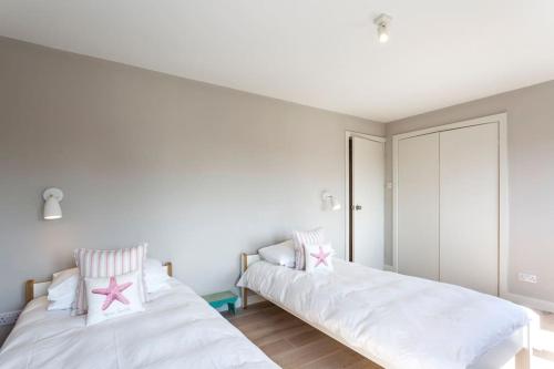 two beds in a room with white walls at Beach house & garden in idyllic village location in West Wittering