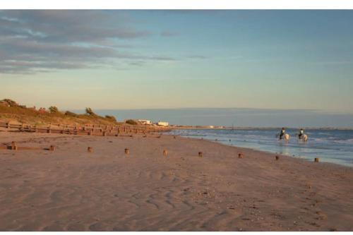 a group of people riding horses on the beach at Beach house & garden in idyllic village location in West Wittering