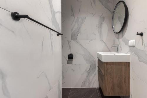 a white bathroom with a sink and a mirror at Scala Apartamenty by Moderna Profit- Łąkowa 60K in Gdańsk