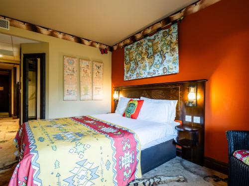 a bedroom with a large bed with orange walls at LEGOLAND(R) Windsor Resort in Windsor